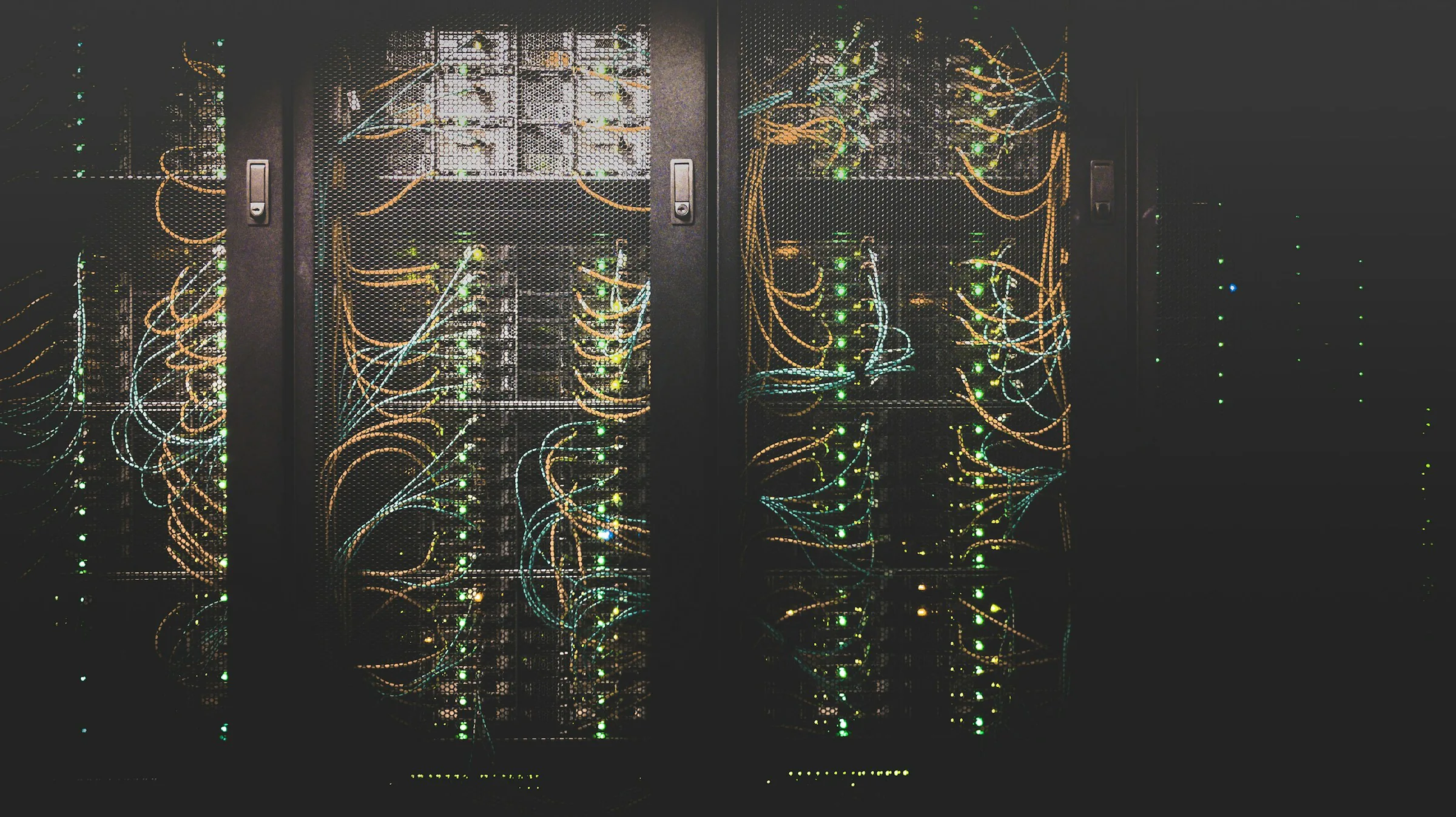 Server racks with network cabling and status lights, the kind of infrastructure OrionAlerts monitors alongside cameras and recorders